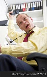 Businessman, trying to strangle himself with a telephone cord, because of too much stress at work