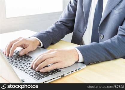 Businessman typing laptop or notebook on wood table in office. Activity in office
