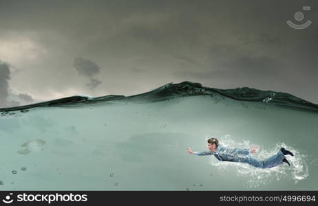 Businessman under water. Young businessman in suit swimming in stormy waters