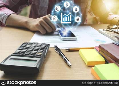 Businessman use smartphone with Currencies sign symbol of Fintech over the Network connection on the office desk, Investment Financial Technology Concept.