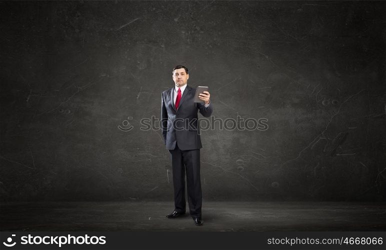 Businessman use tablet pc. Adult businessman in concrete room using tablet pc