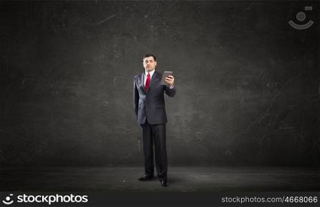 Businessman use tablet pc. Adult businessman in concrete room using tablet pc