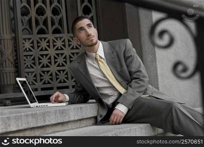 Businessman using a laptop and day dreaming