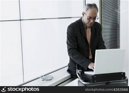 Businessman using a laptop in the waiting room of an airport