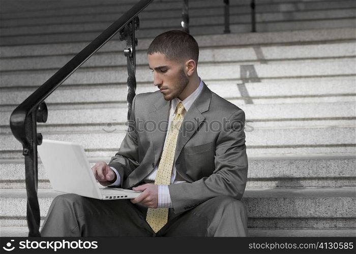 Businessman using a laptop on the staircase