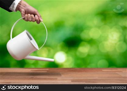 Businessman using a watering can with empty space table for customization representing corporate reforestation policy for sustainable future. Forest regeneration and ecological recovery concept. Alter. Businessman using a watering can to nourish earth globe with tree. Alter
