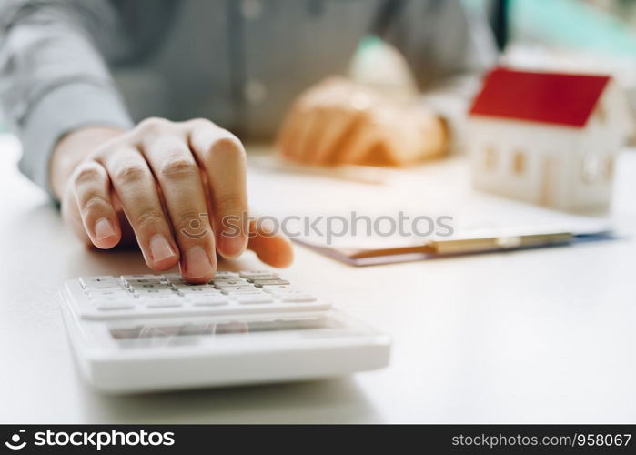 Businessman using calculator calculate budget about house contract mortgage in the office room.