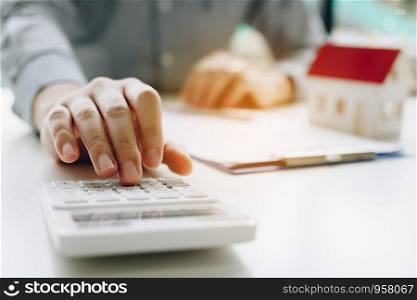 Businessman using calculator calculate budget about house contract mortgage in the office room.