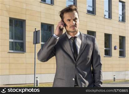 Businessman using cell phone against office building