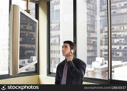 Businessman Using Cell Phone and Watching TV