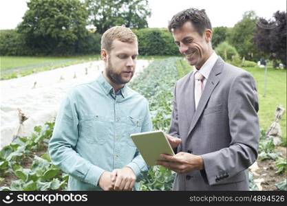 Businessman Using Digital Tablet During Meeting With Farmer In Field