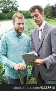 Businessman Using Digital Tablet During Meeting With Farmer In Field