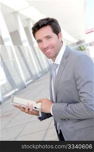 Businessman using electronic tablet outside a building