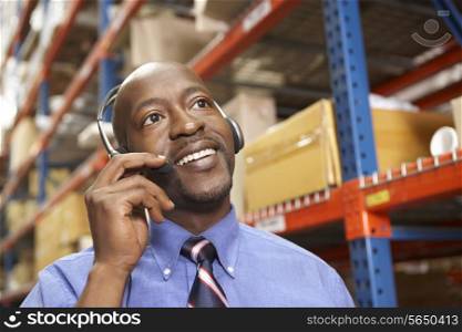 Businessman Using Headset In Distribution Warehouse