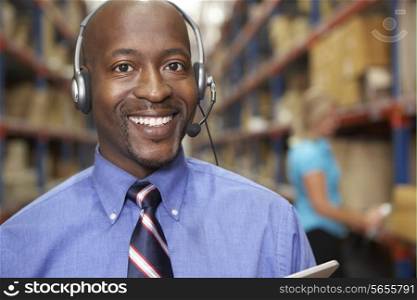 Businessman Using Headset In Distribution Warehouse