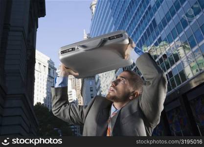 Businessman using his briefcase as a shade