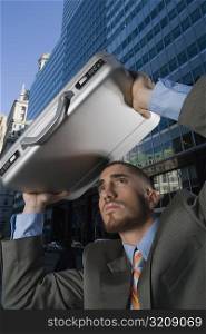 Businessman using his briefcase as a shade