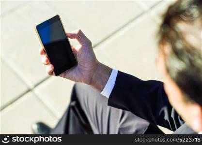 Businessman using his smartphone in the street. Man wearing suit with cellphone.