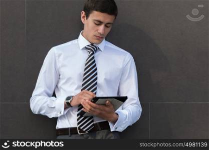 Businessman using his tablet computer outdoors near office building