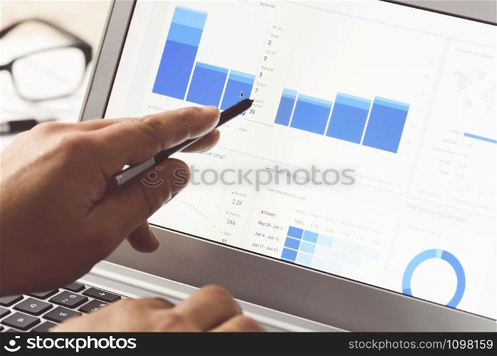 Businessman using internet analytics in the office on the touch screen of his laptop (reduced tone)