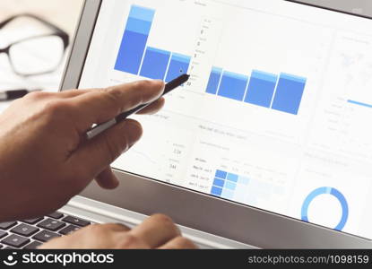 Businessman using internet analytics in the office on the touch screen of his laptop (reduced tone)