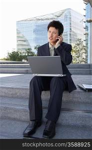 Businessman Using Laptop and Cell Phone