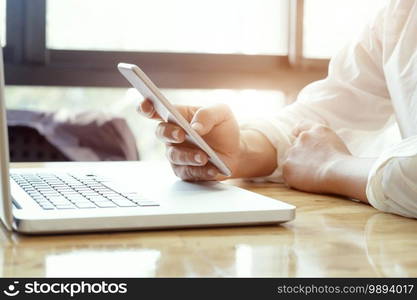 Businessman using laptop and mobile phone for online communication.