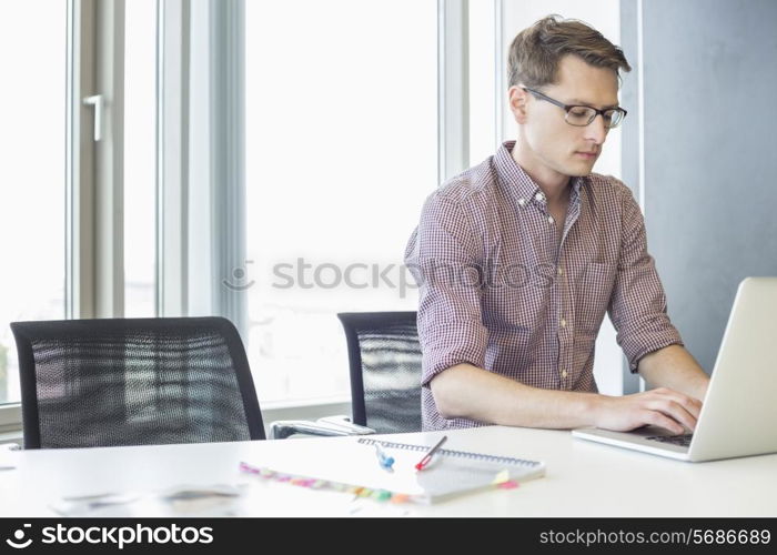 Businessman using laptop at desk in creative office