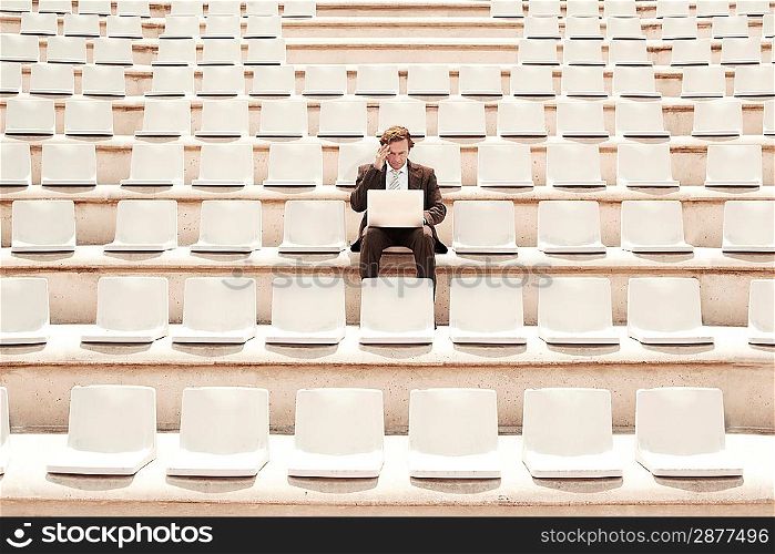 Businessman Using Laptop in Auditorium