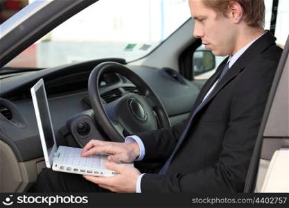 Businessman using laptop in his car