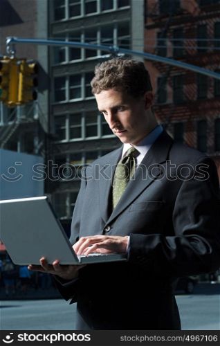 Businessman using laptop in street