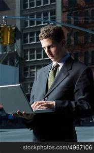 Businessman using laptop in street