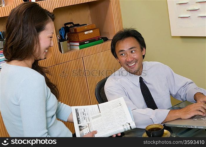 Businessman Using Laptop Talking to Co-worker