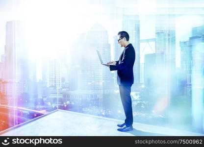 Businessman using laptop with generic office background , night scene .