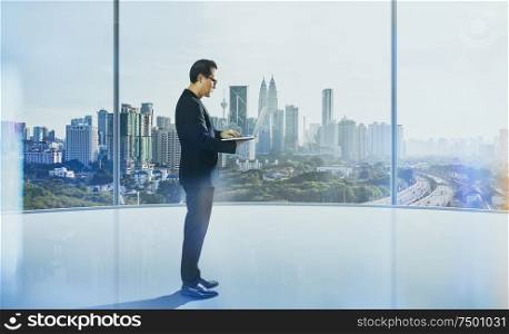 Businessman using laptop with generic office background , night scene .