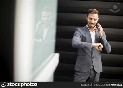 Businessman using mobile phone and looking on the watch in Financial District