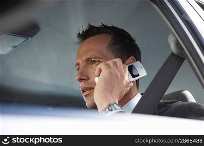 Businessman using mobile phone in car low angle view