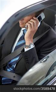 Businessman using mobile phone in car mid section elevated view