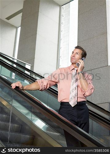 Businessman using mobile phone on escalator