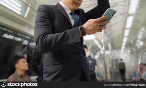 Businessman using mobile phone on public train . Urban city lifestyle commuting concept .