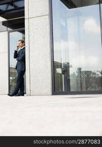 Businessman using mobile phone outside office building