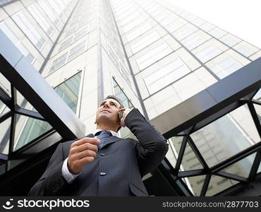 Businessman using mobile phone outside office (low angle view)