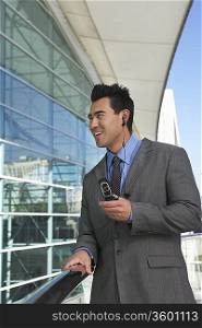 Businessman using mobile phone with earpiece office building
