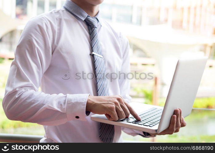 businessman using modern laptop for working at personal space outdoor, wireless connection internet on his notebook computer.