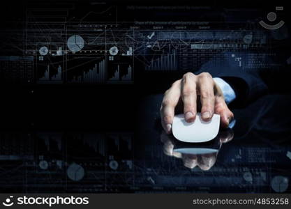 Businessman using mouse. Hand of businessman in suit on dark background using wireless computer mouse