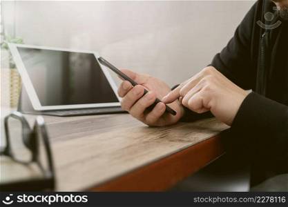 businessman using smart phone for mobile payments online shopping and digital tablet docking keyboard computer on wooden desk in modern office