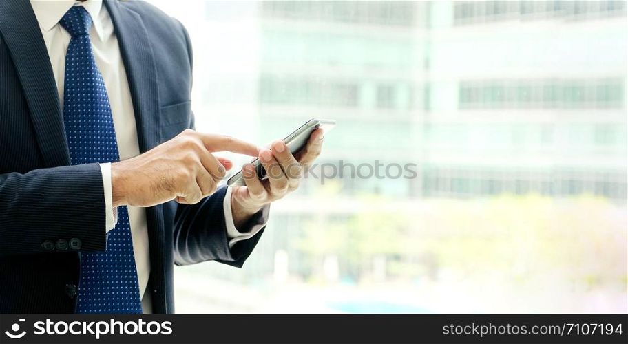 Businessman using smart phone over blur office background with copy space for text, people on phone, technology and lifestyle