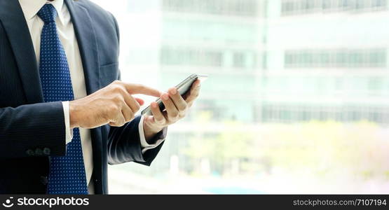 Businessman using smart phone over blur office background with copy space for text, people on phone, technology and lifestyle