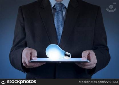 businessman using tablet computer growing  light bulb as concept