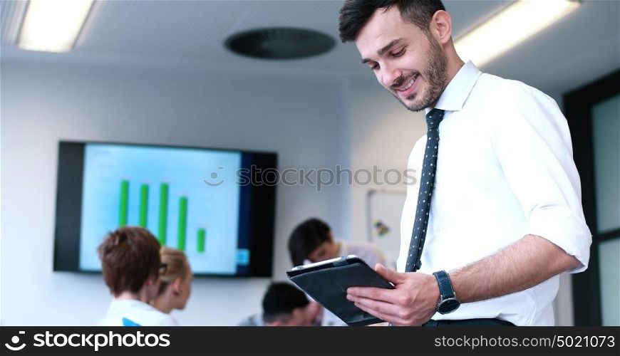 Businessman using tablet computer in office with coworkers in background